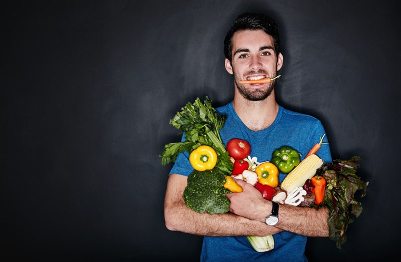 YOUNG MAN CARRYING AN WRMFUL OF VEGETABLES
