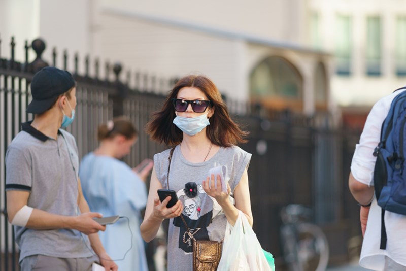 WOMAN WITH FACE MASK AMONG OTHER PEOPLE IN THE BACKGROUND
